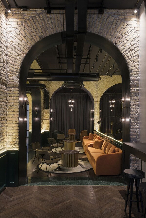 A modern interior with a brick wall, a curved archway, a sofa, and a bar area.