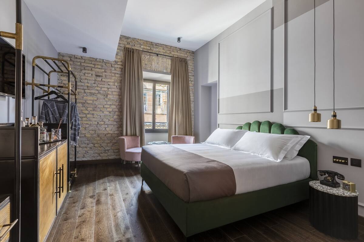 A modern bedroom with a large bed, a wardrobe, a seating area, and a view through a window.