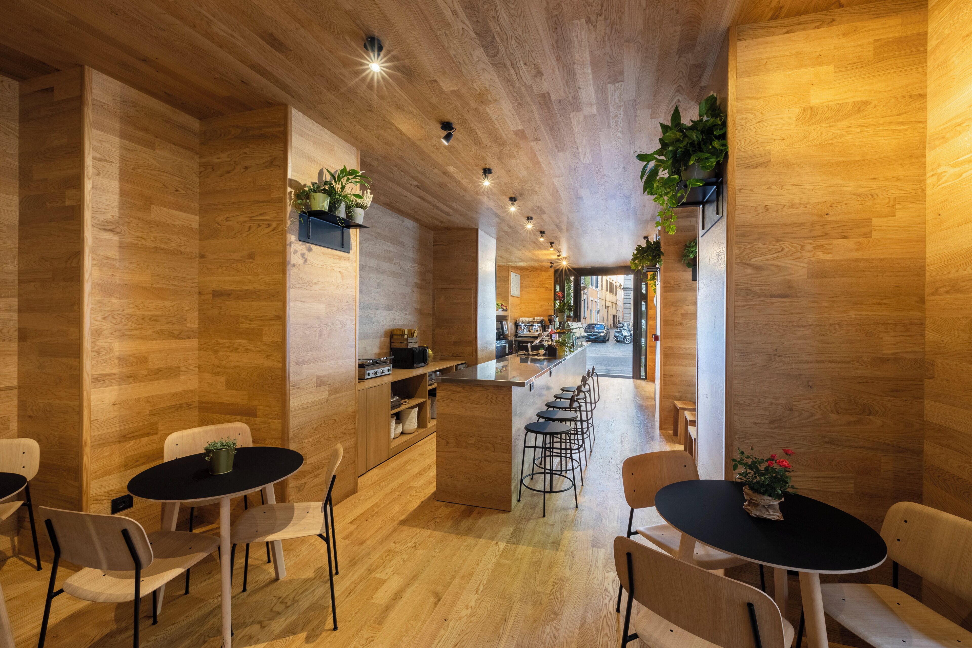 A modern interior with wooden flooring and walls, a central bar area, and seating arrangements.
