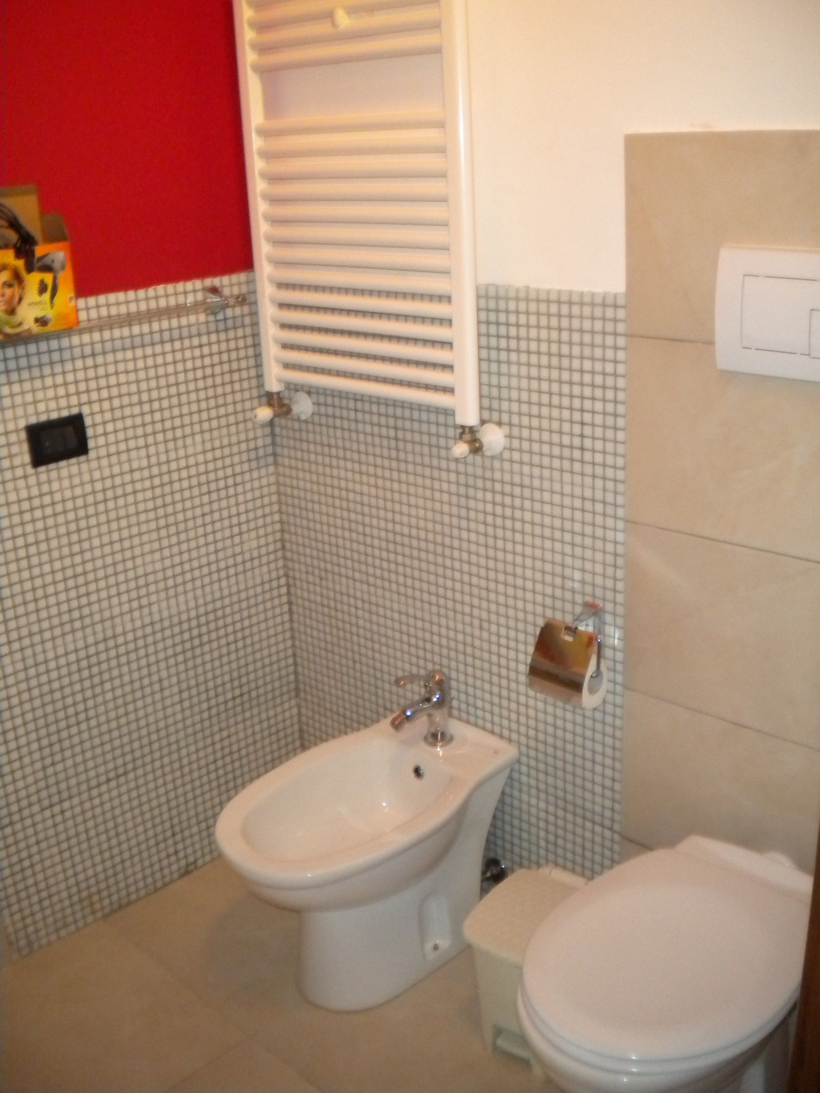 A bathroom with a bidet, toilet, and a towel rack.