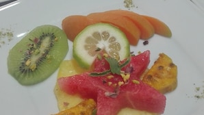 A table with multiple square plates of food, each containing a variety of fruits and a yellow base, possibly a sauce or puree. - Agriturismo Rifugio di Dedalo (Sant'Angelo Muxaro)
