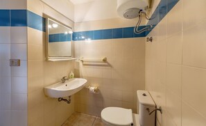 A small bathroom with a white sink, mirror, and toilet. There is a towel rack above the sink and a toilet paper holder on the wall. - Villetta Ginepro Verde (Trinità d'Agultu e Vignola)