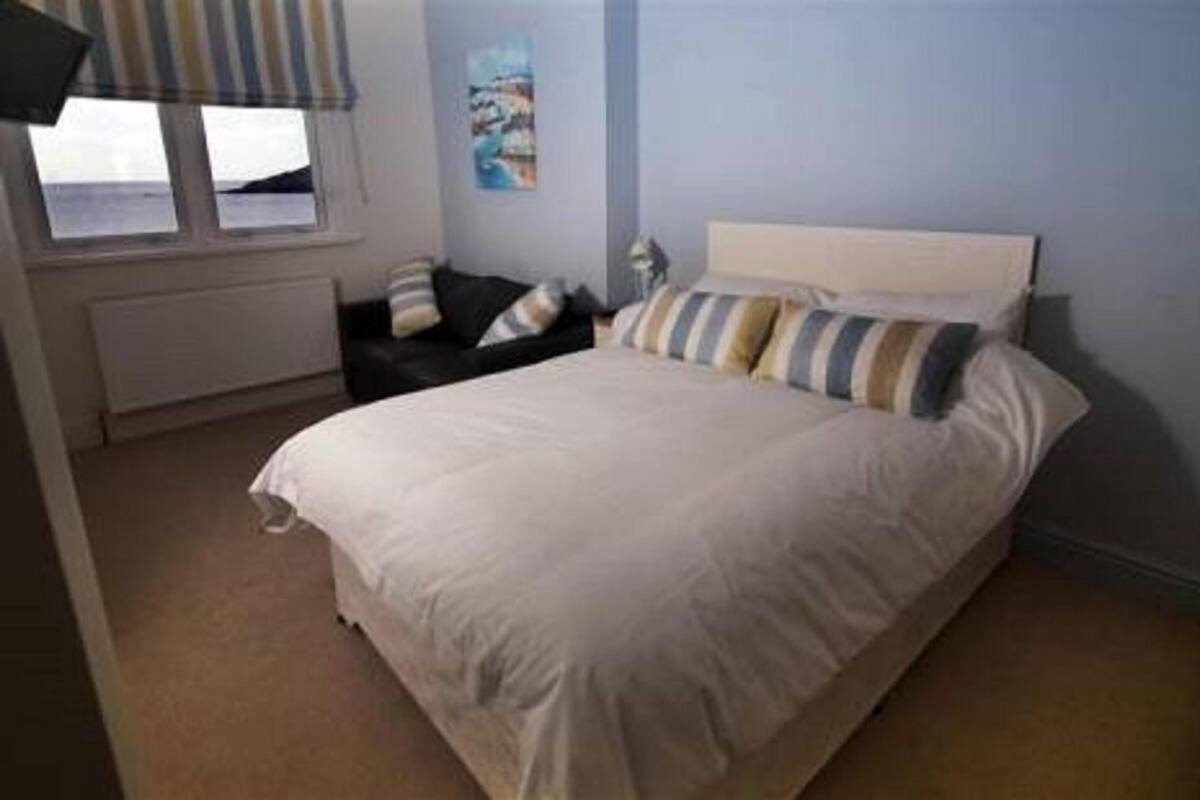 A bedroom with a bed, a nightstand, a lamp, and a window with blinds.