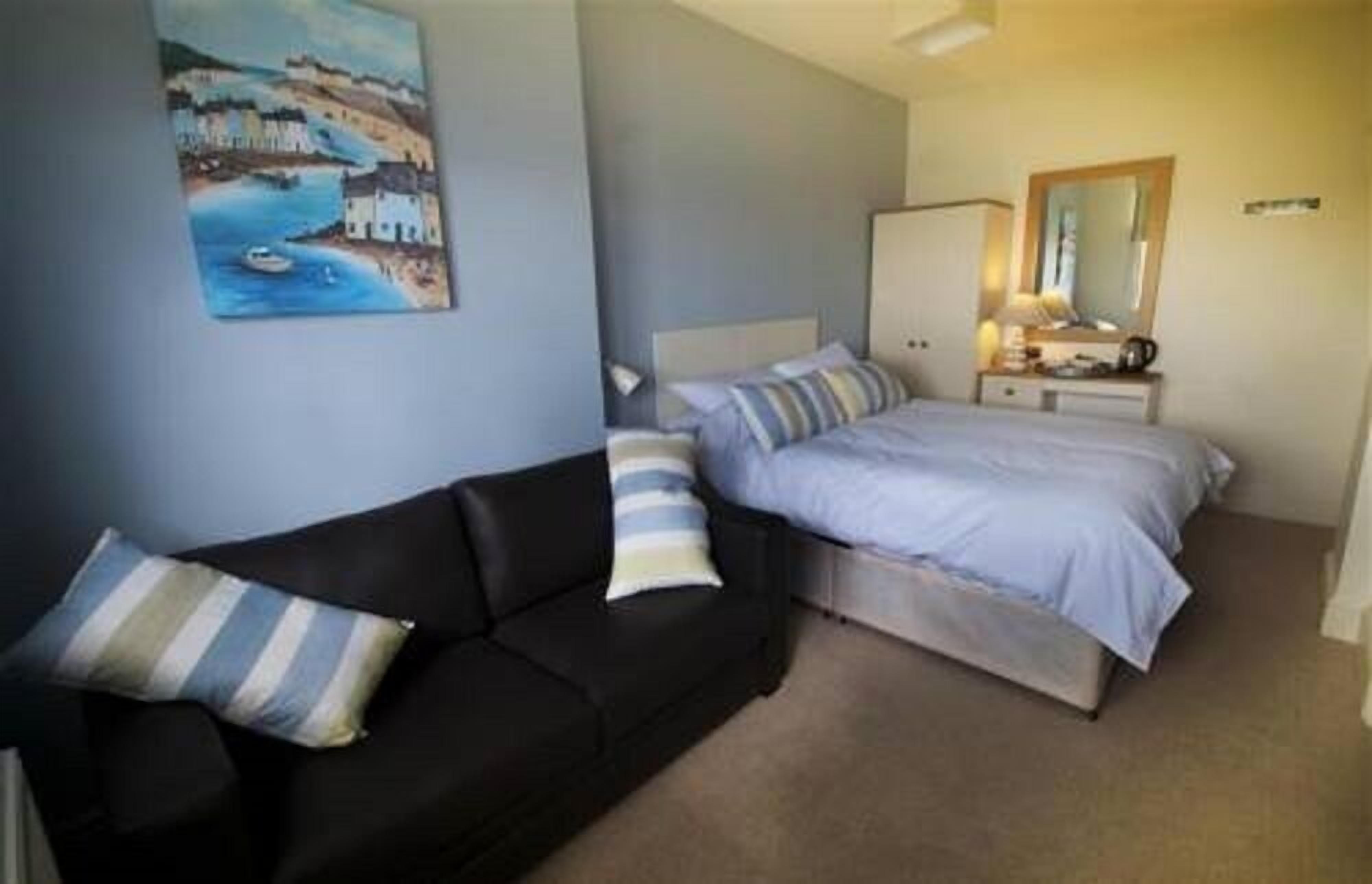 A bedroom with a bed, a bedside table, a lamp, and a painting on the wall.