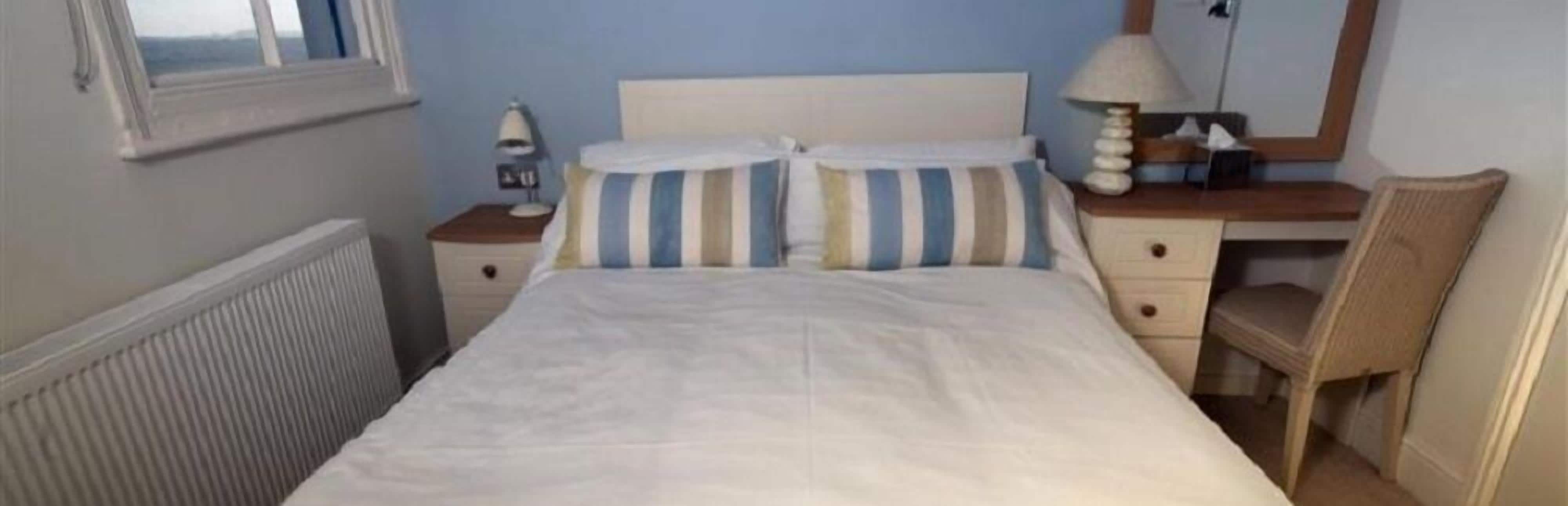 A bedroom with a bed, a nightstand, a chair, a dresser, and a window.