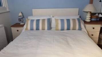 A bedroom with a bed, a nightstand, a chair, a dresser, and a window.