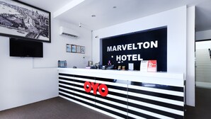 A reception desk with a sign reading "Marvelton Hotel" and a large "OYO" logo.