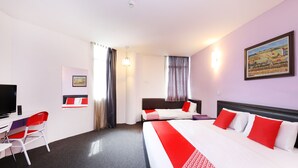 A hotel room with two beds, a desk with a chair, a television, and a painting on the wall.