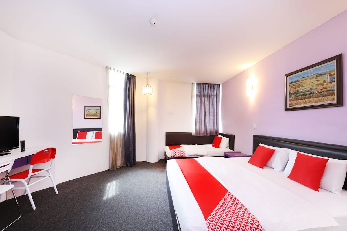 Habitación de hotel con dos camas, un escritorio con silla, un televisor y un cuadro en la pared.
