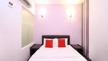 Ein Hotelzimmer mit einem Bett, zwei Nachttischen, einem Fenster und einer Klimaanlage.