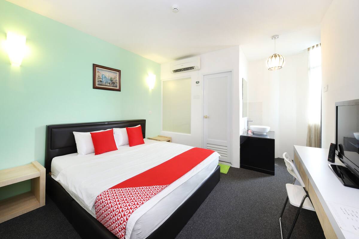 Una habitación de hotel con cama, escritorio, computadora, televisión y baño.