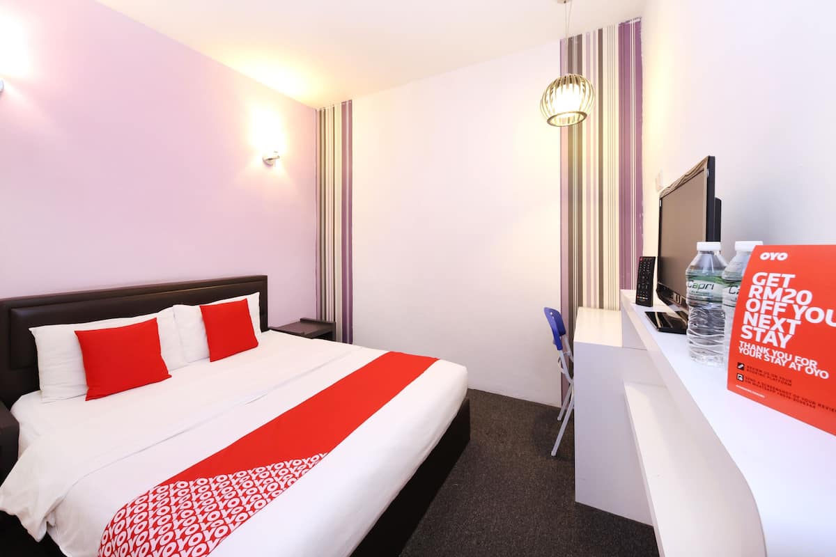 Habitación de hotel con cama, escritorio, silla, televisor y un cartel que ofrece descuento en la próxima estadía.