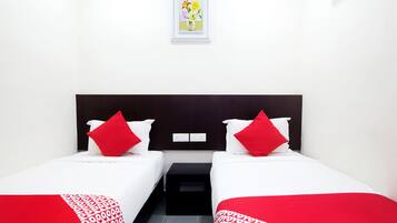 A hotel room with two beds, each with white bedding and red accents, a small bedside table, a framed picture on the wall, and a white air conditioning unit.