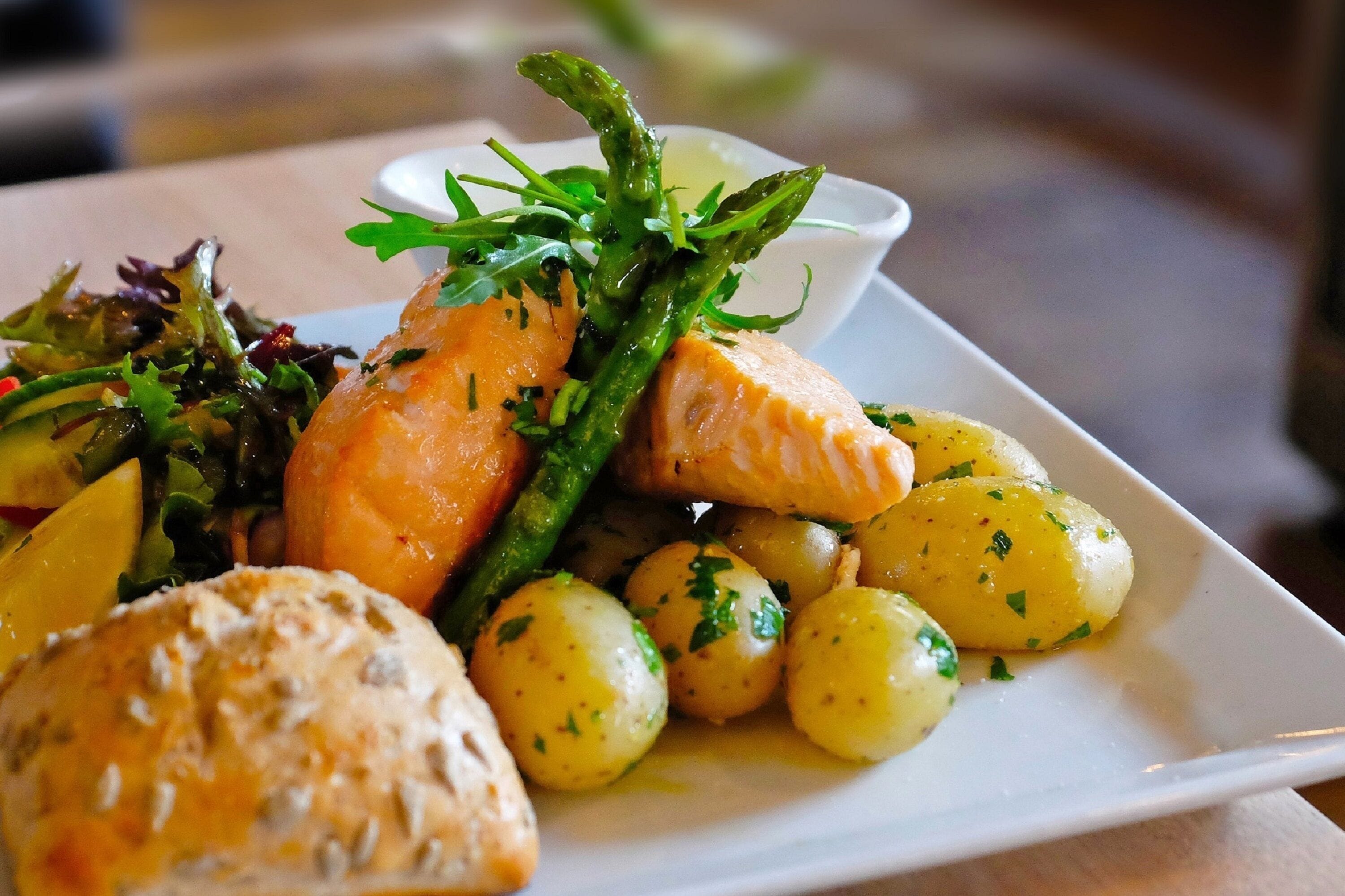 A plate of food with salmon, asparagus, potatoes, and a salad.