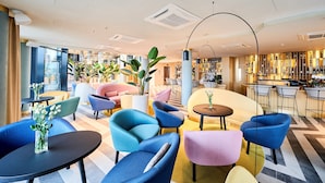 A modern lounge area with colorful seating, a bar, and large windows.