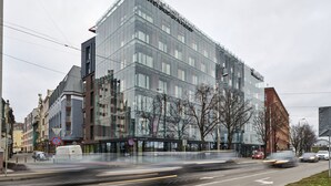 A modern hotel with a glass facade, located at a street corner with a pedestrian walkway. - Wellton Riverside SPA Hotel (Riga)