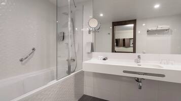 Une salle de bain moderne avec une douche à parois de verre, un lavabo blanc avec un miroir et un porte-serviettes.