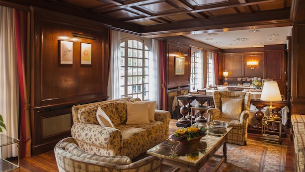 A spacious living room with a wooden ceiling, large windows, and a cozy seating area with a coffee table.