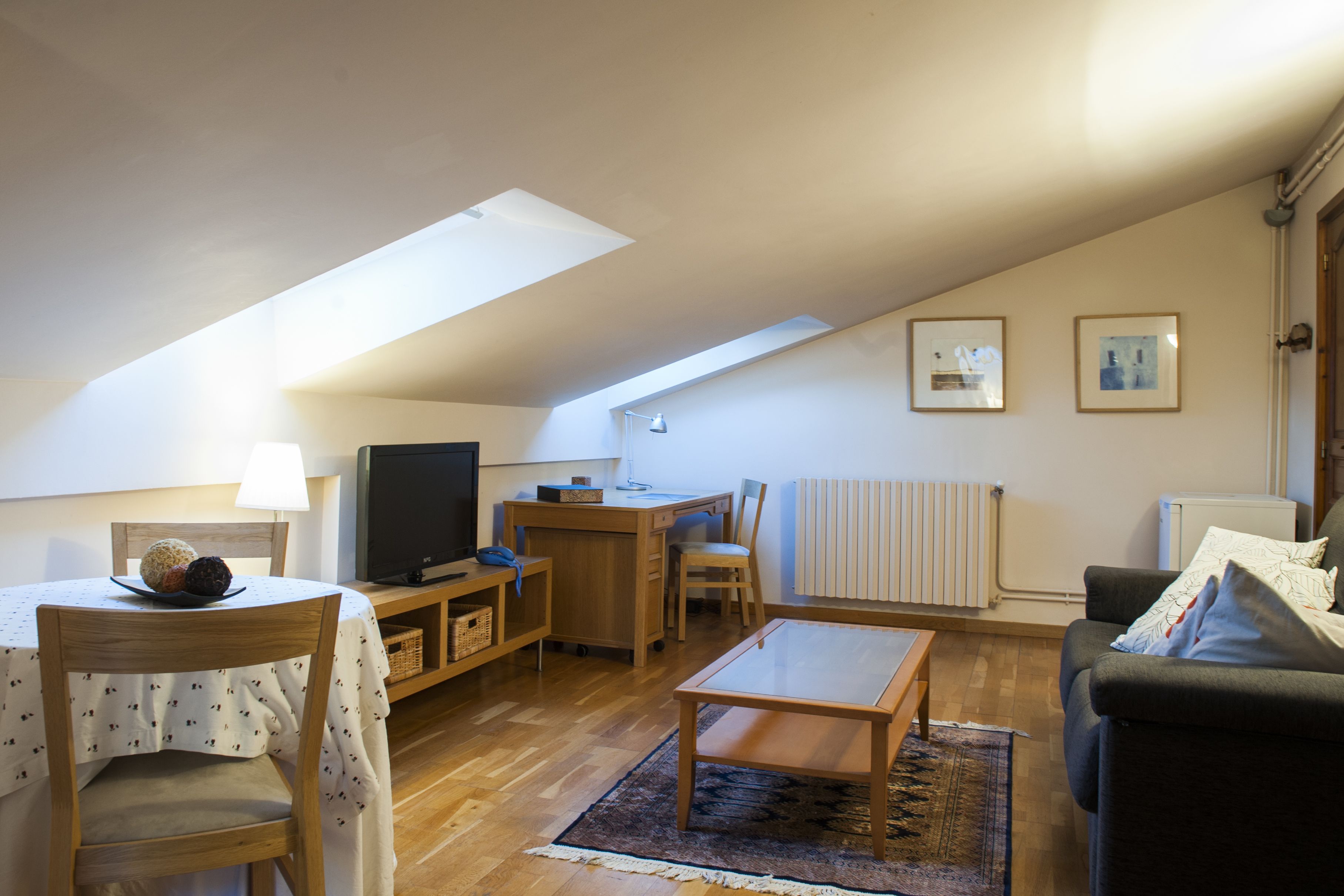 Un salón acogedor con una mesa de madera, un sofá, un televisor y un escritorio.