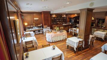 A restaurant with wooden floors, white tablecloths, and wooden chairs.