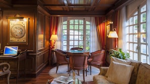 Una habitación con techo de madera, una mesa redonda con sillas, un sofá y un escritorio con un ordenador portátil.