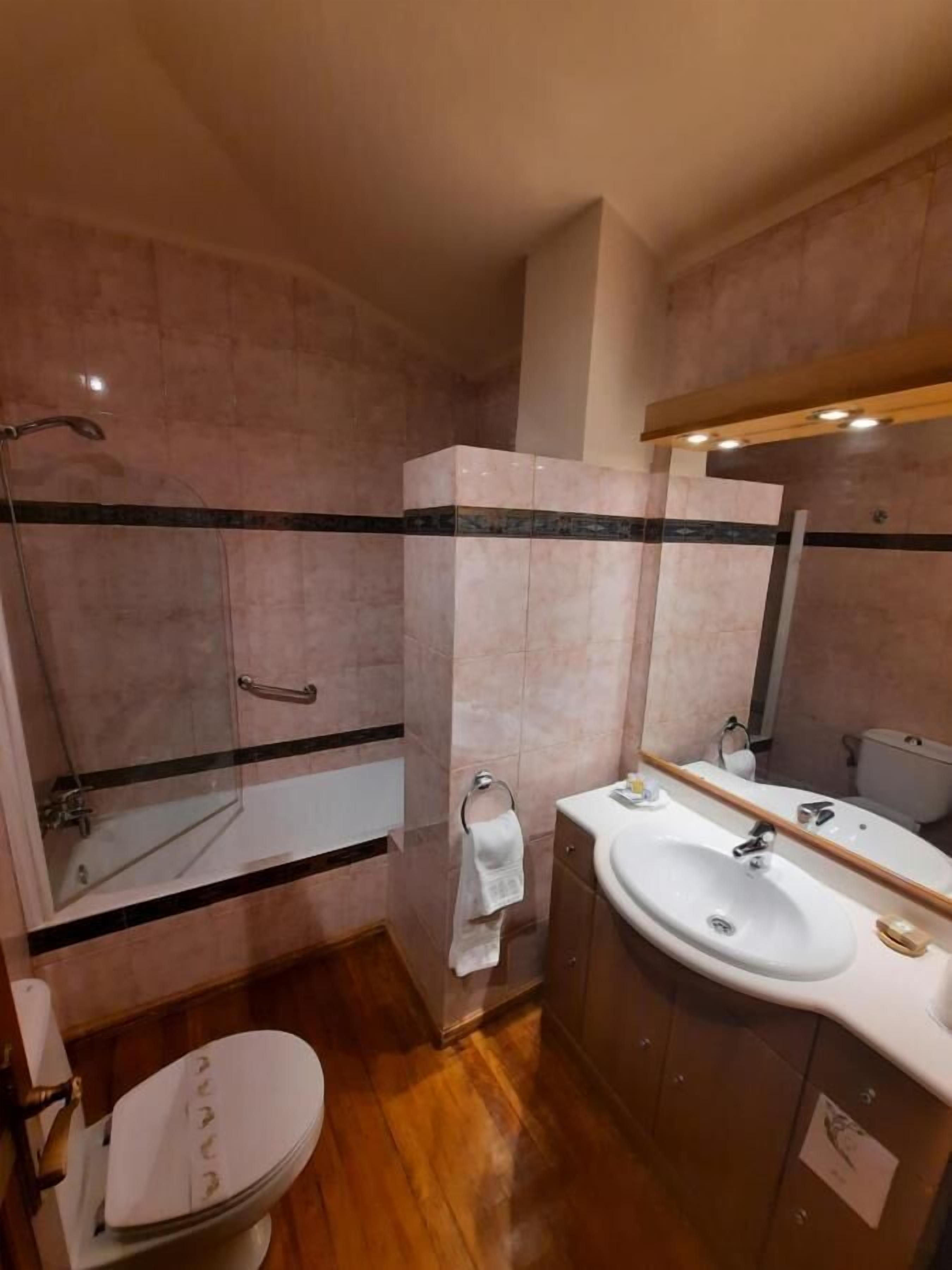 Un baño con ducha, inodoro, lavamanos y espejo.