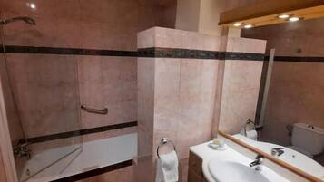 Un baño con ducha, inodoro, lavamanos y espejo.
