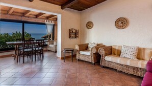 A cozy patio area with a dining table and chairs, a wicker sofa, and a small round table. - Villetta Hemingway (Trinità d'Agultu e Vignola)