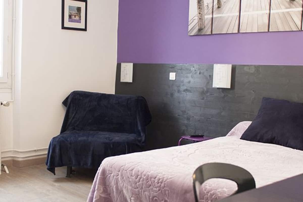 A bedroom with two beds, a chair, and a radiator.