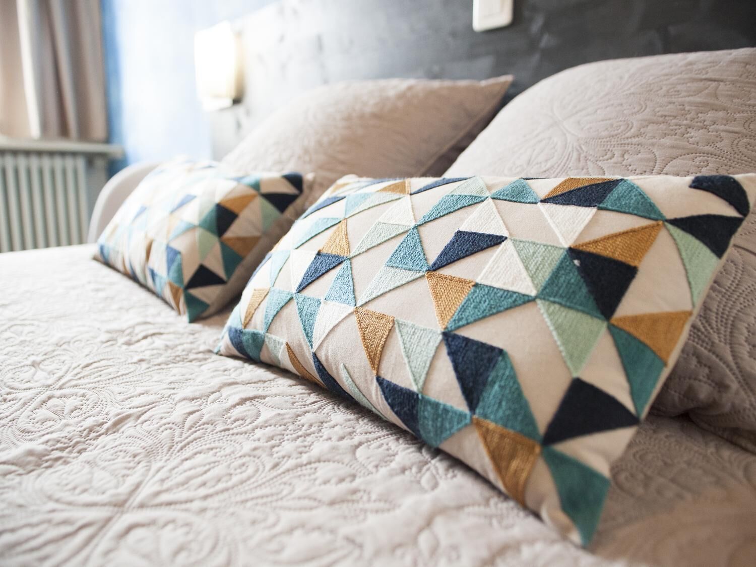 A bed with a patterned quilt and two pillows with a geometric design.