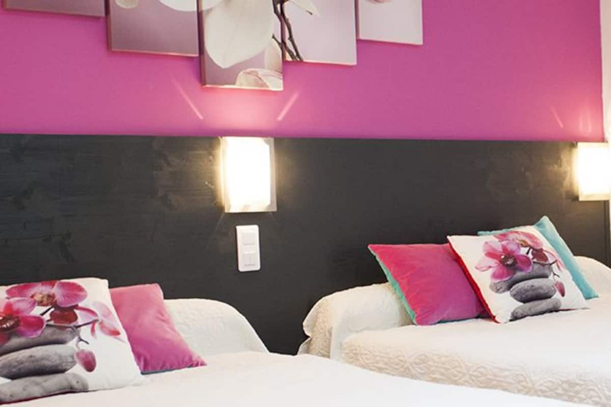 A hotel room with two beds, each with a pillow and a wall-mounted light.