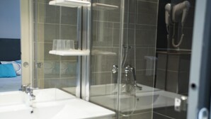Un baño moderno con cabina de ducha de vidrio, un lavabo blanco y un cabezal de ducha manual.