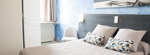 Un dormitorio con cama, almohadas, una silla y un radiador.