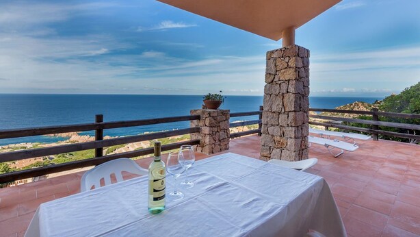A terrace with a table set for two, overlooking the sea.