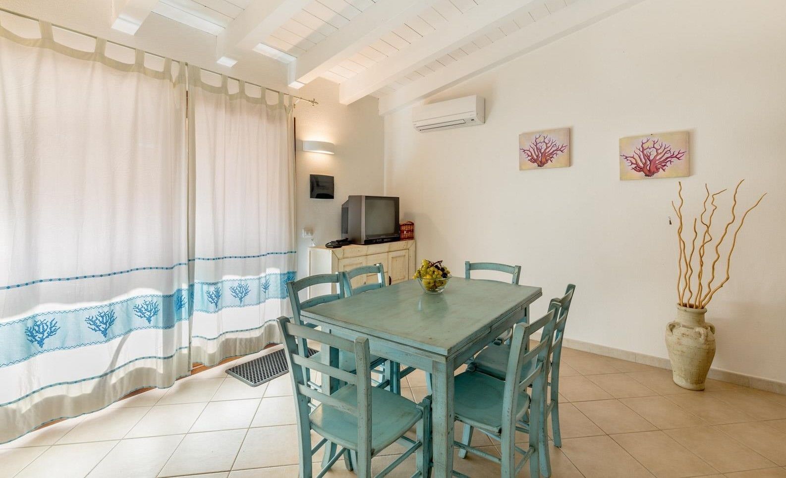 A dining area with a table and chairs, a television, and artwork on the wall.