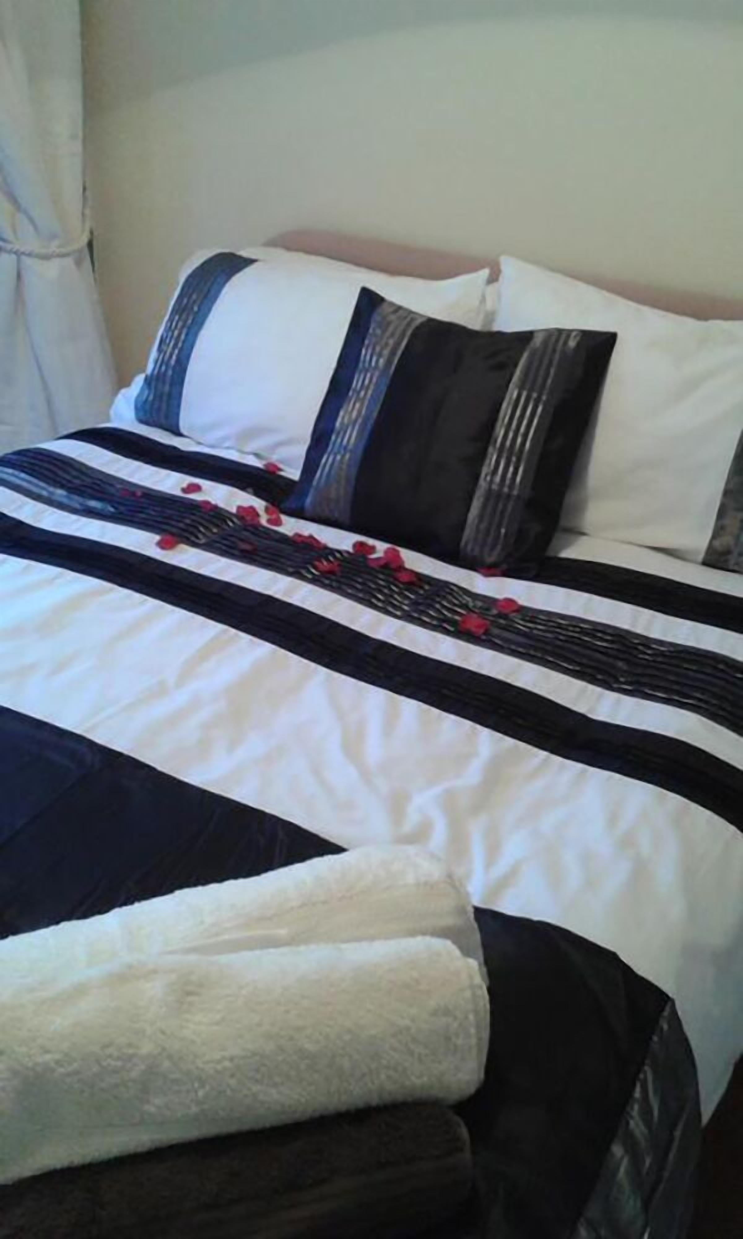 Un lit bien fait, avec une couverture à rayures, des oreillers et une serviette blanche pliée.