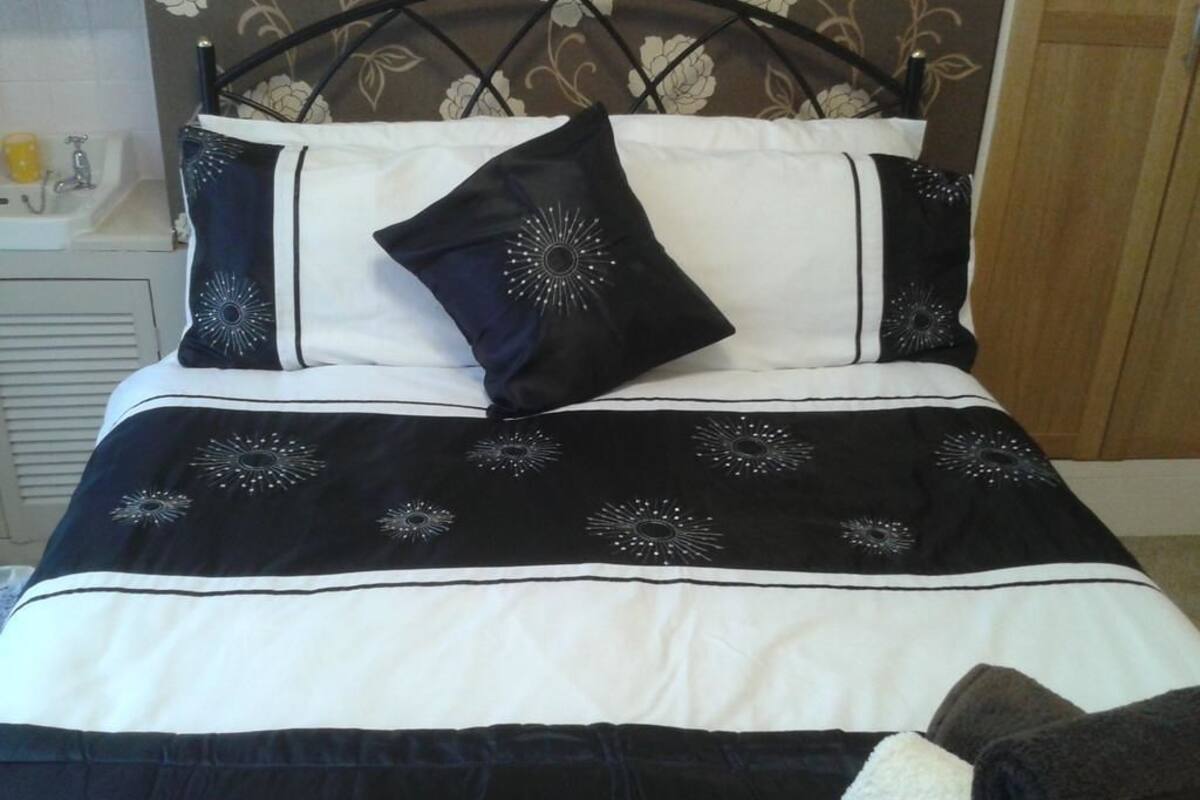 A bed with a black and white bedspread, two pillows, and a headboard with a floral pattern.