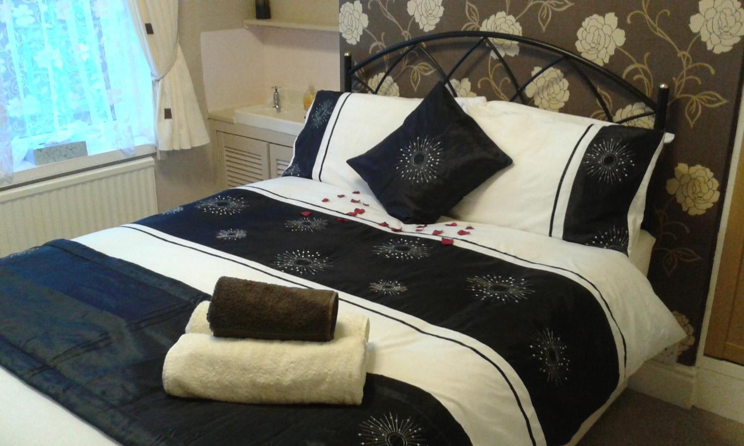 A neatly made bed with a black and white bedspread, two pillows, and a folded towel.