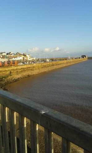 A waterfront view with a concrete walkway, a row of buildings, and a calm river. - St Hilda Guest House (Bridlington)