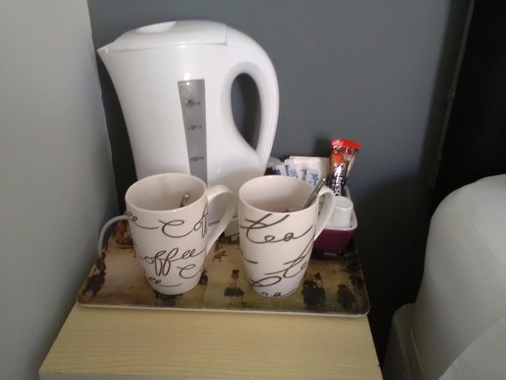 A tray with two coffee mugs and a white electric kettle on a table.