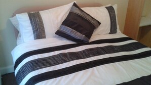 A bed with a striped bedspread and two pillows. - St Hilda Guest House (Bridlington)