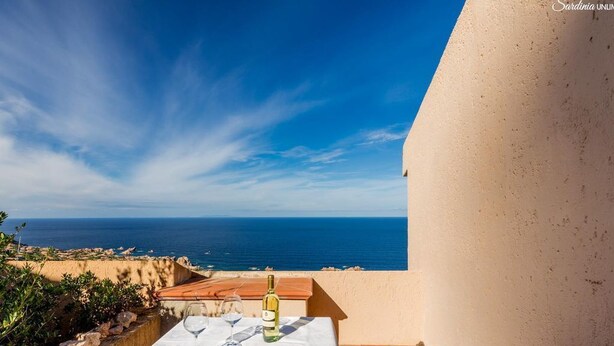 A table set with a bottle of wine and glasses, overlooking the sea.