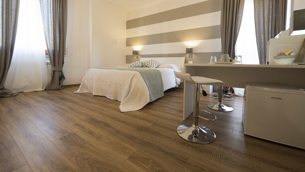A hotel room with a bed, a desk, a chair, and a minibar. - Suite Simonetta (Sarzana)