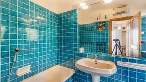 A bathroom with blue patterned tiles, a white sink, and a bathtub. - Villa Mariù e Amelie (Aglientu)