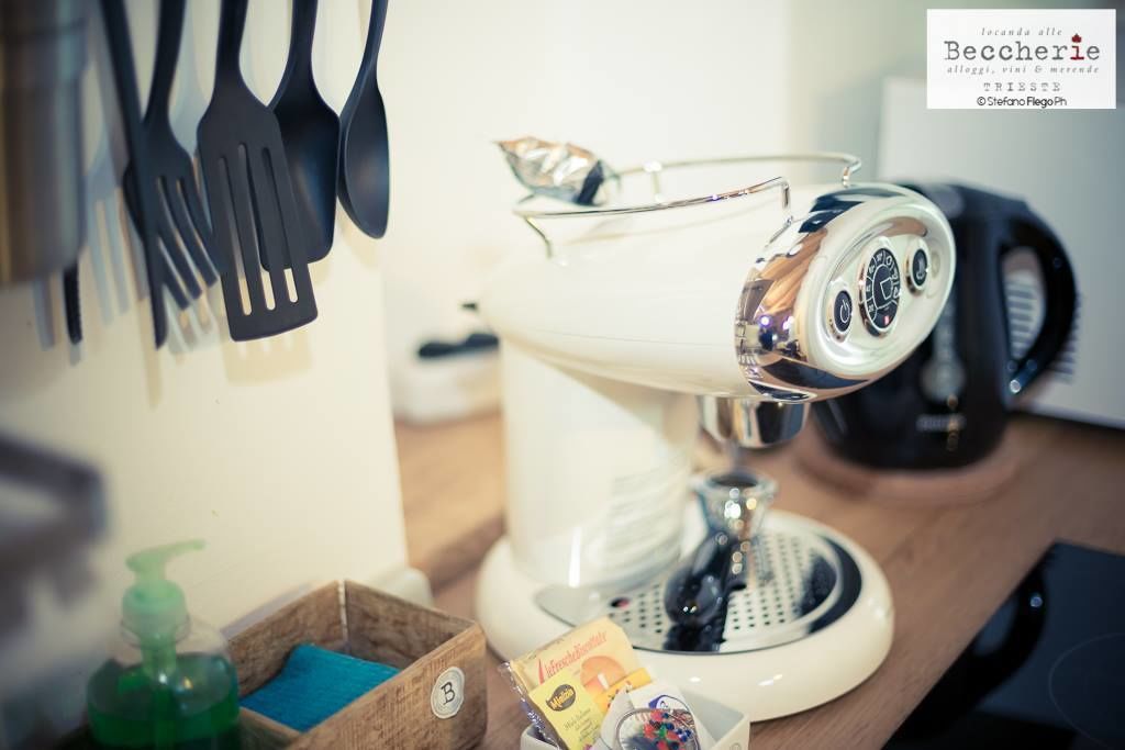 A coffee machine on a counter with a bottle of hand soap and a box of tissues.