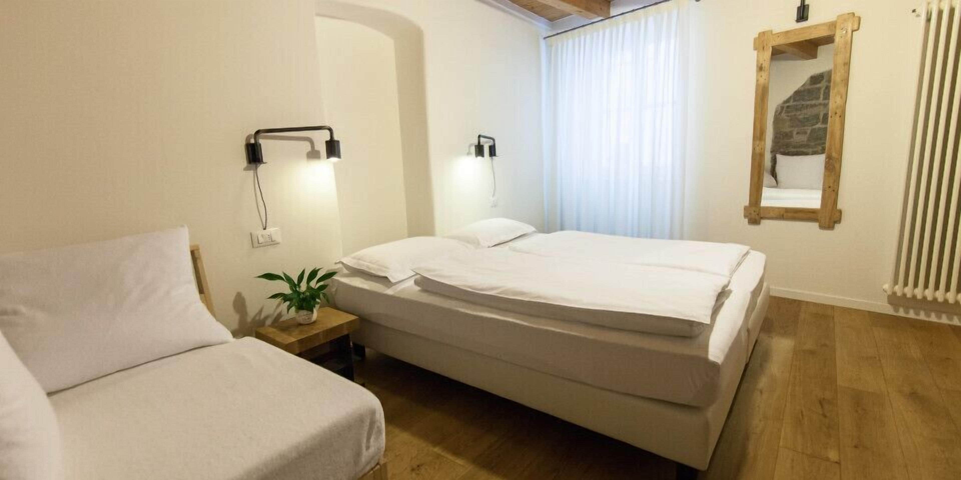 A bedroom with a bed, bedside tables, a lamp, a potted plant, and a mirror.