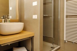 A bathroom with a large white sink, a mirror, and a glass shower enclosure. - Locanda alle Beccherie (Trieste)