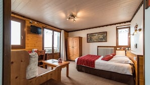 Una habitación acogedora con una cama, un escritorio de madera, una silla, una ventana y un radiador.
