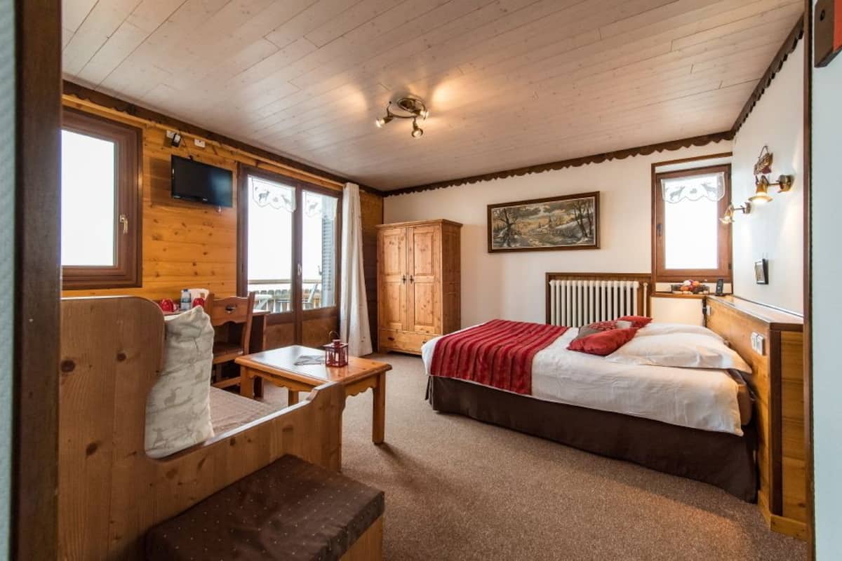 Une pièce confortable avec un lit, un bureau en bois, une chaise, une fenêtre et un radiateur.