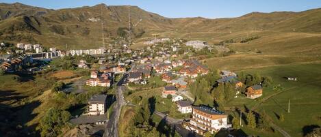 An aerial view of a residential area with houses, roads, and a hilly landscape.
